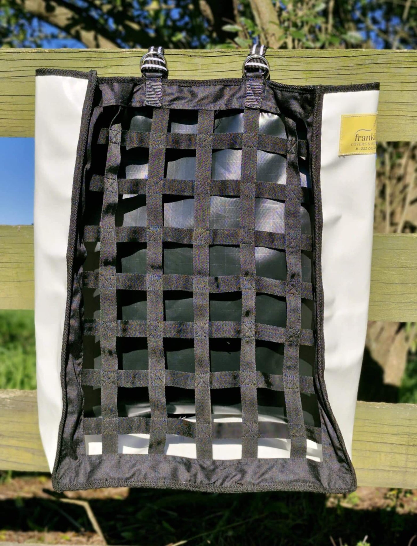 FCR Slow Feed Haybag hanging on a fence, designed to promote natural foraging and reduce hay waste.