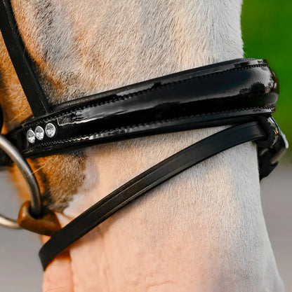 Close-up of a Unicorn Pony bridle featuring a glossy black patent noseband with crystal detailing.