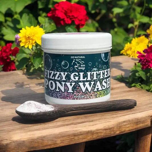 Eco Horse Fizzy Glitter Pony Wash jar with a wooden scoop, surrounded by colorful flowers in a garden.