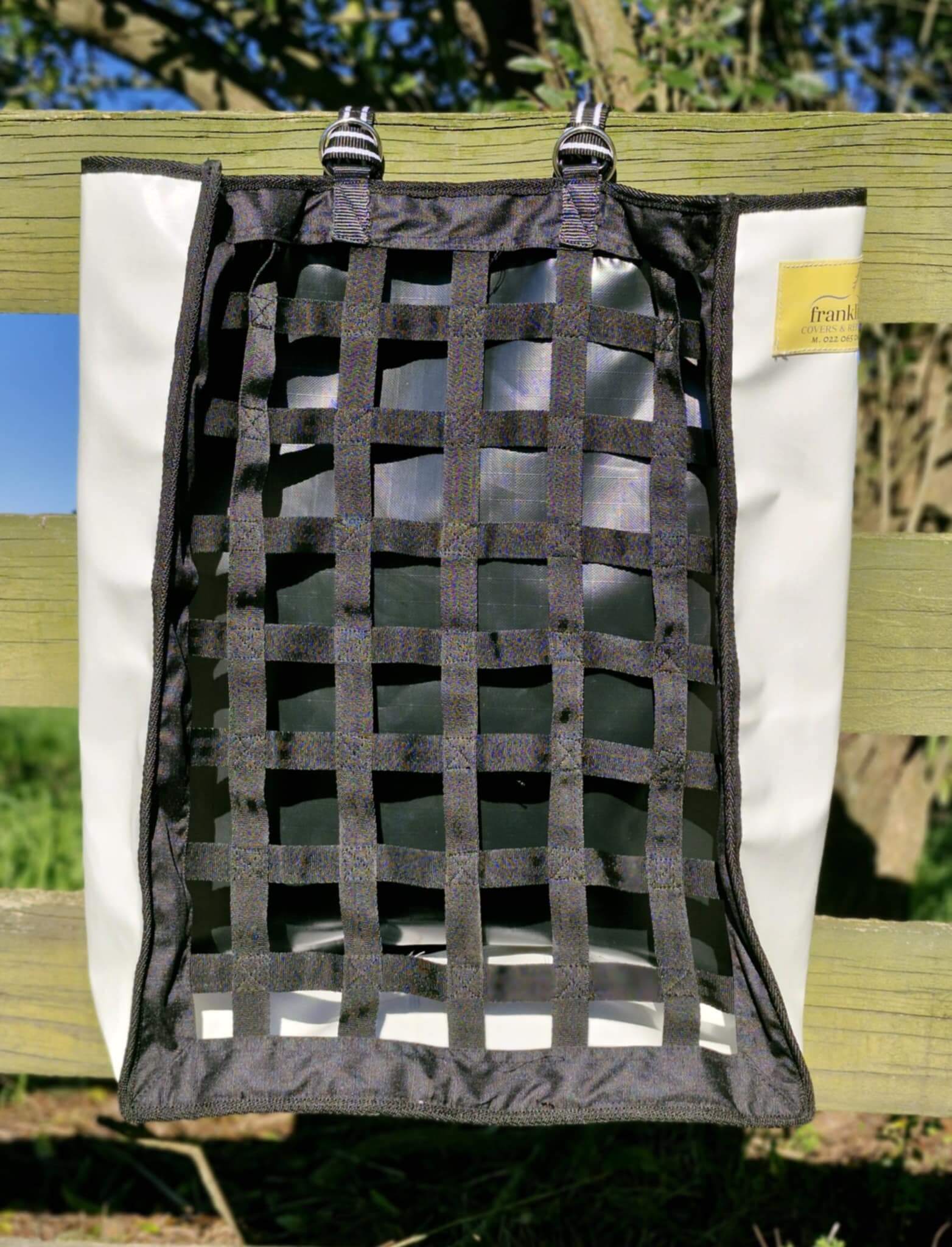 FCR Slow Feed Haybag hanging on a fence, designed to promote natural foraging and reduce hay waste.